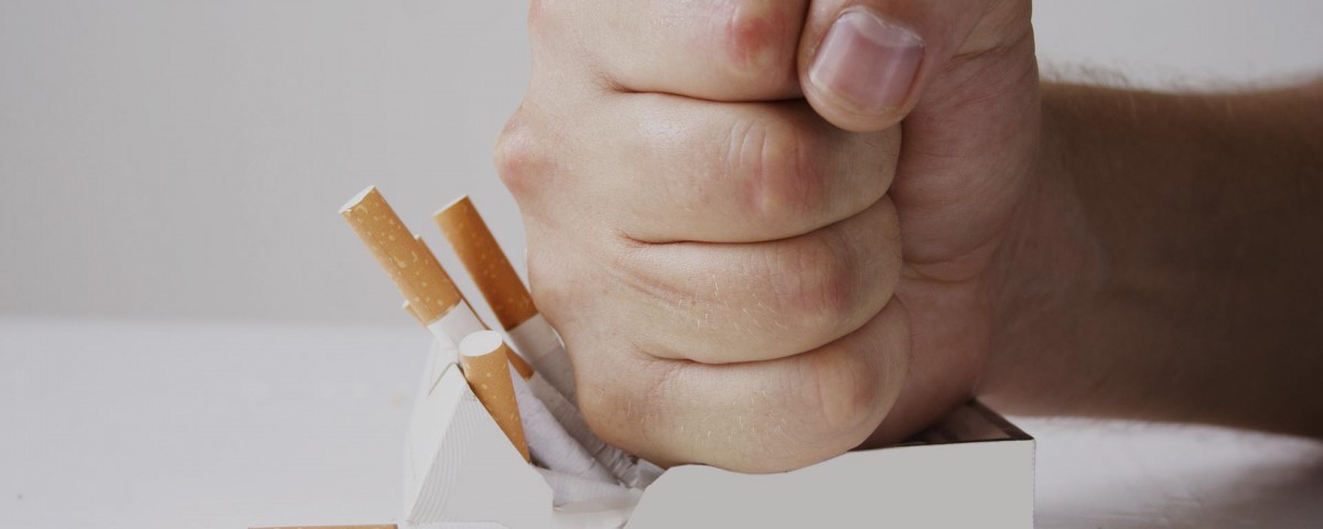 puño aplastando paquete de tabaco para no engordar al dejar de fumar